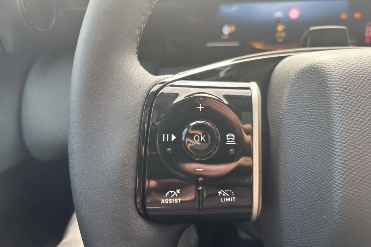 Gros plan sur les commandes noires multifonctions au volant cuir du Citroën C5 Aircross blanc avec toit noir.