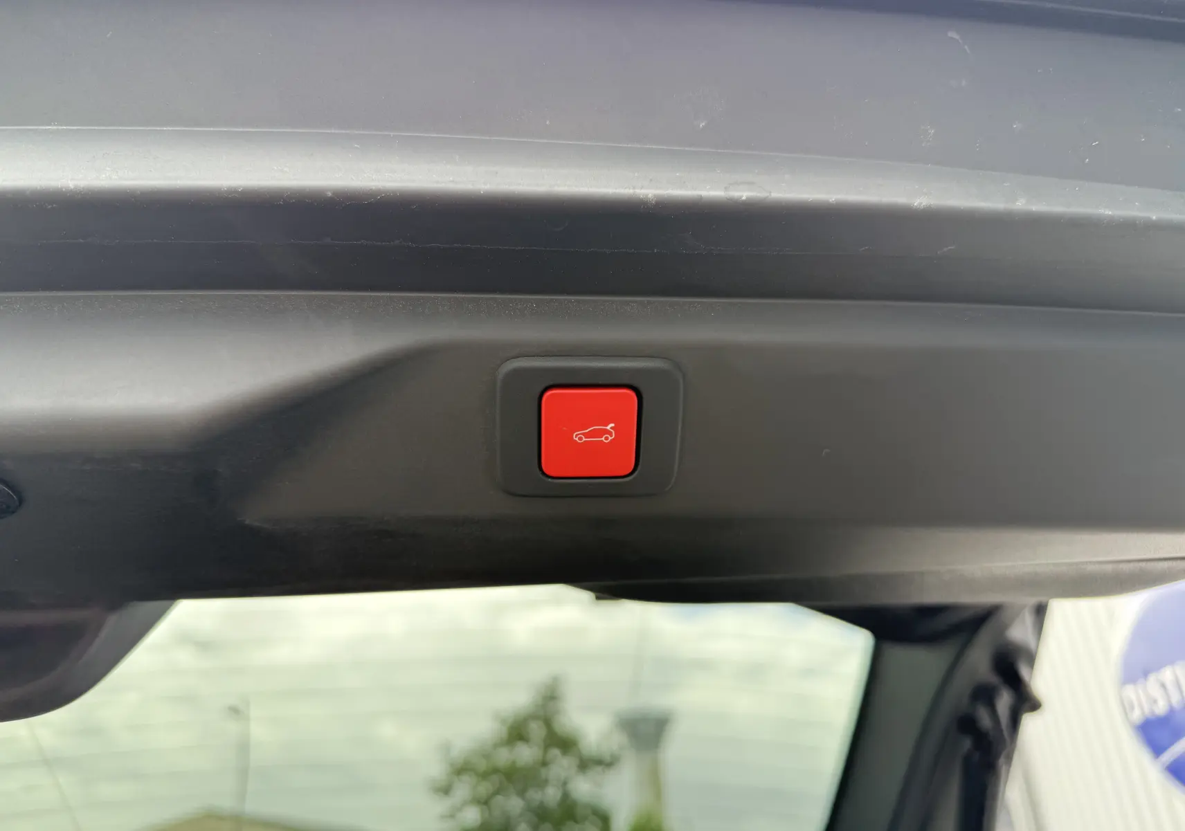 Bouton rouge de fermeture électrique du hayon visible depuis l'intérieur du coffre du Peugeot 3008 blanc toit noir.