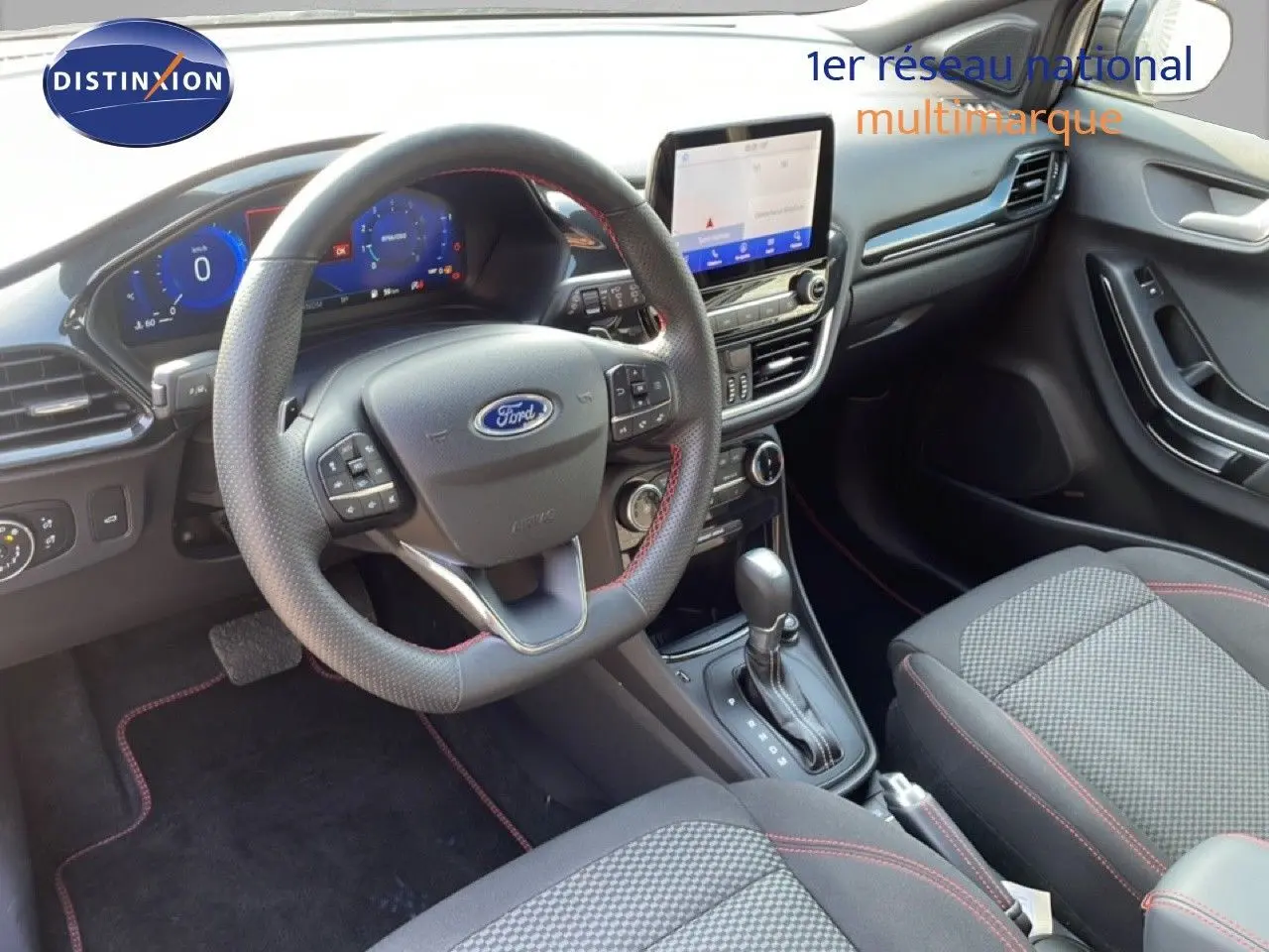 Vue intérieure avant droite du Ford Puma 2023, volant cuir noir avec surpiqûres rouges et écran tactile central.