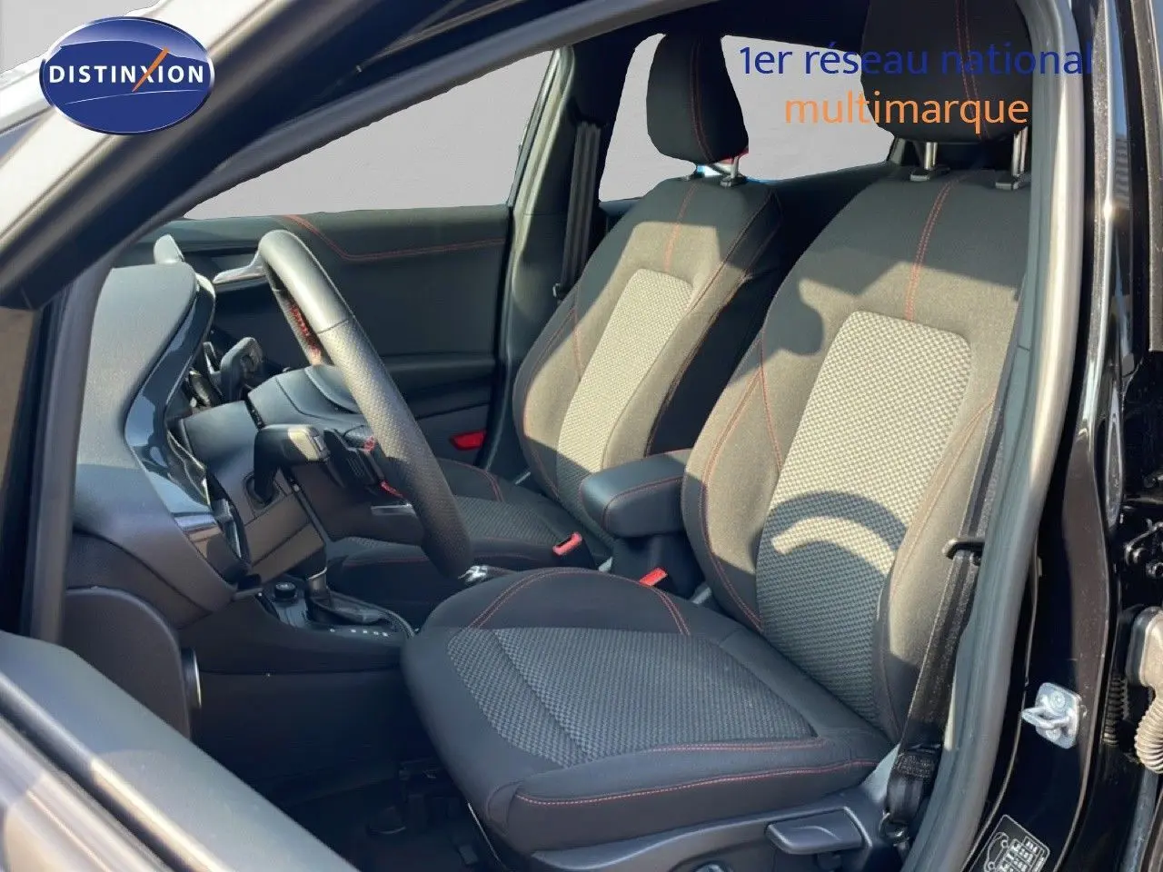 Vue intérieure côté gauche du Ford Puma noir agate métal 2023, sièges tissu avec surpiqûres rouges et volant cuir multifonction.