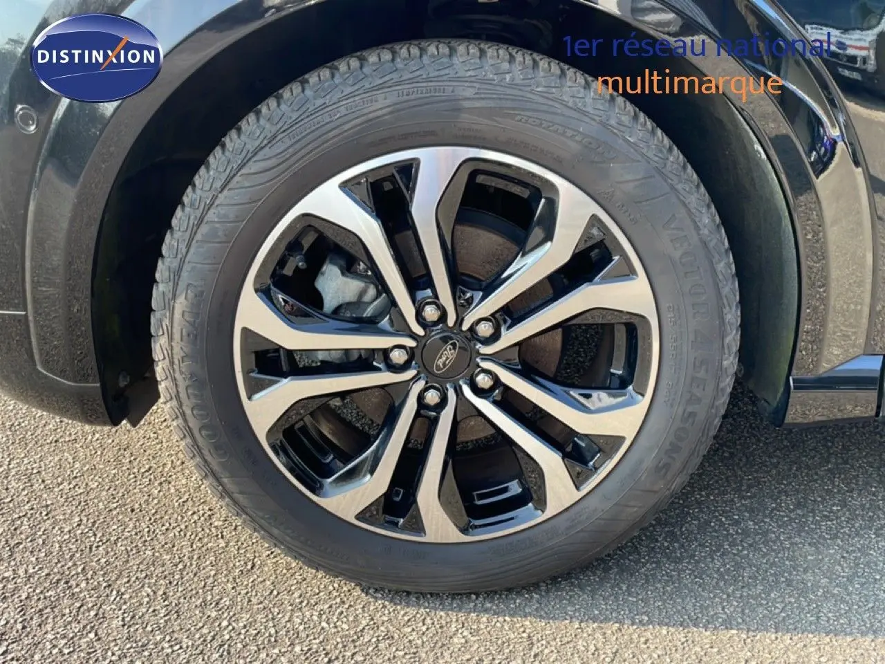 Gros plan sur la roue avant gauche du Ford Puma noir agate métal avec jante alliage bicolore et pneu Goodyear.