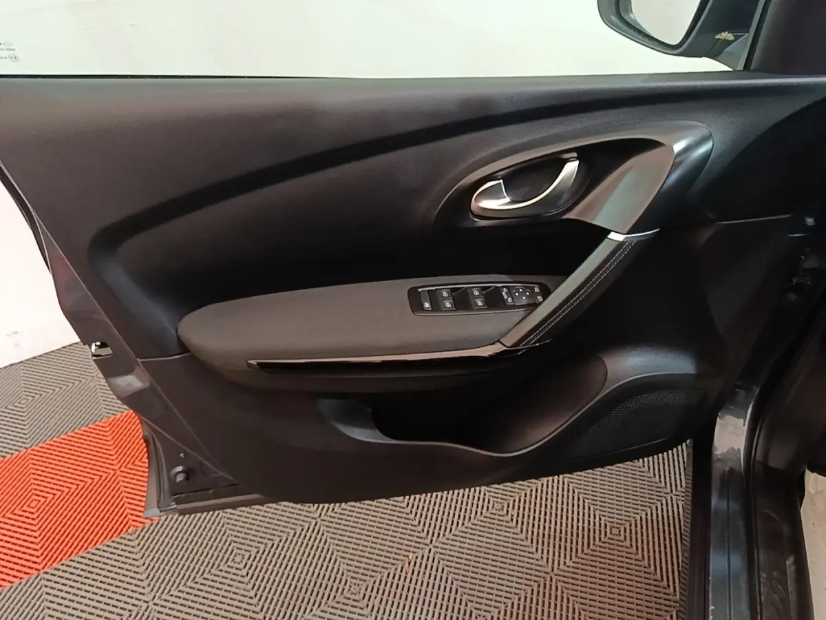 Vue intérieure de la porte avant gauche du Renault Kadjar gris foncé, avec commandes des vitres et poignée argentée.
