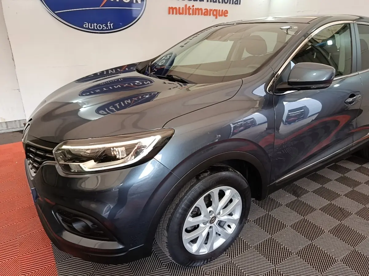 Vue 3/4 avant droit d’un Renault Kadjar Business gris foncé avec phares allumés et jantes argentées.