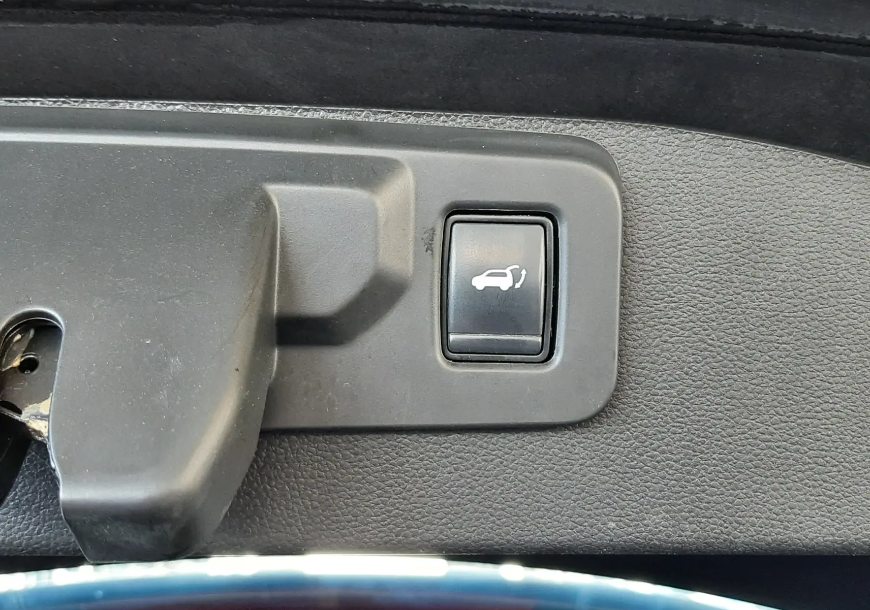 Bouton d'ouverture électrique du hayon sur le bord intérieur du coffre d'un Renault Austral Bleu Iron 2023.