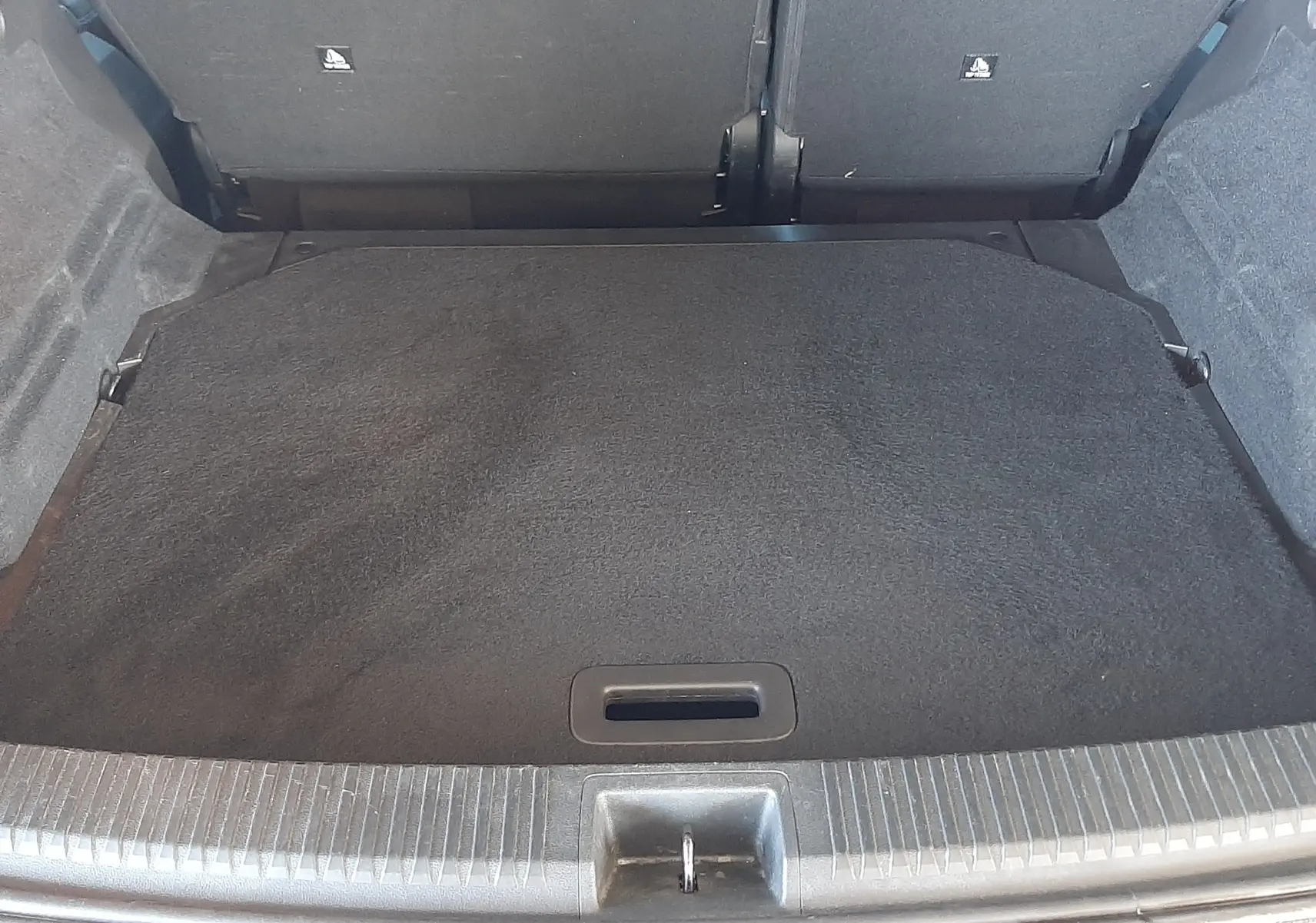 Vue du coffre ouvert d'un Renault Austral E-Tech 200 Bleu Iron, montrant l'espace de chargement et la banquette arrière rabattue.