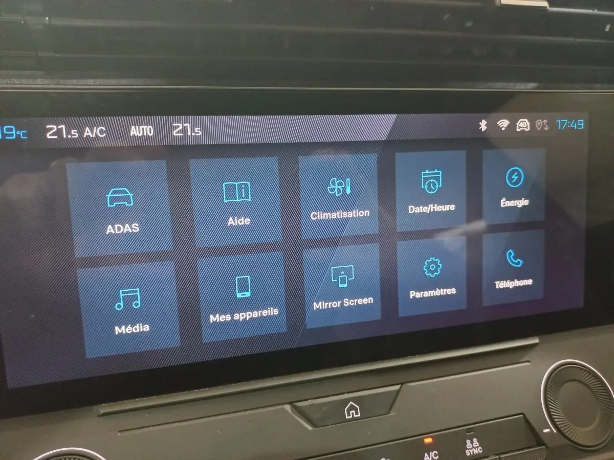 Écran tactile central de la Peugeot 308 PHEV 2025 affichant les menus climatisation, aide et énergie.
