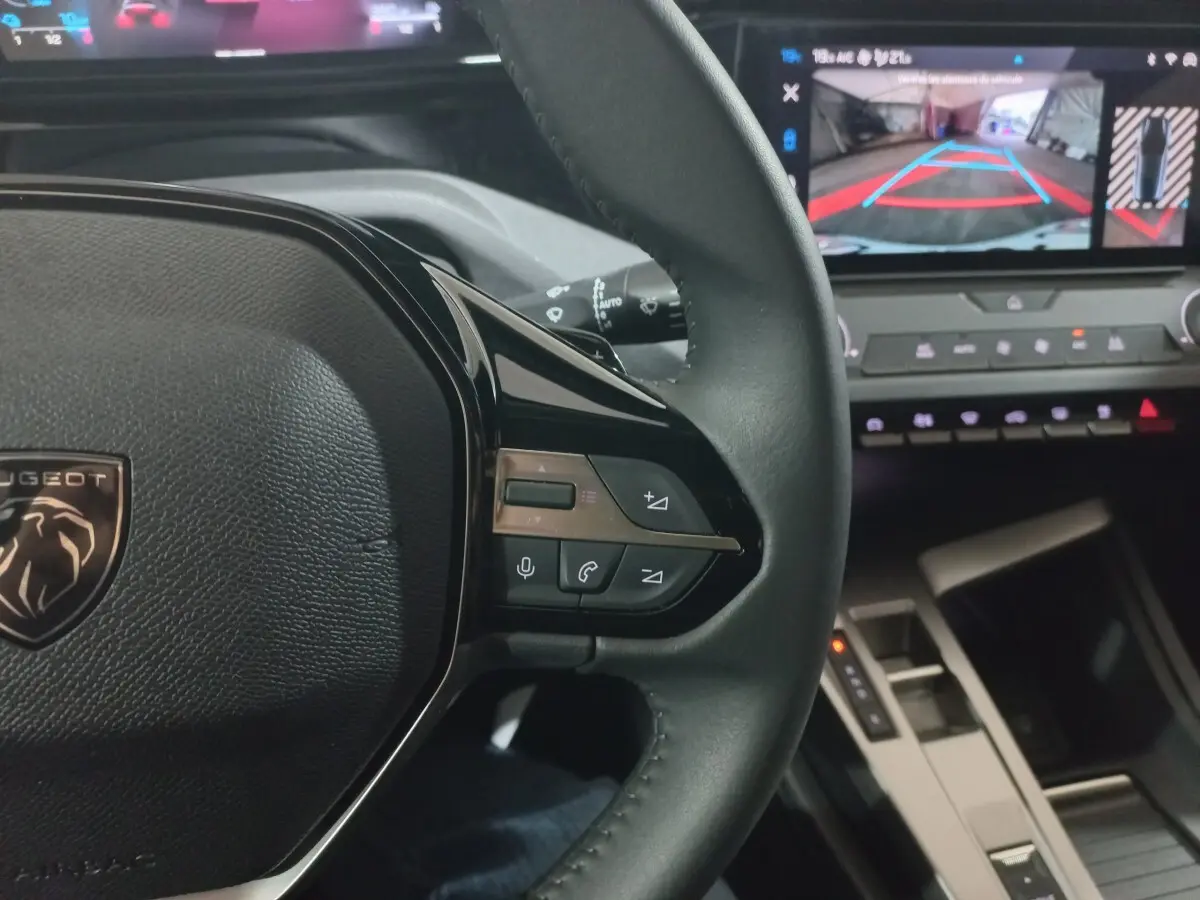 Vue intérieure rapprochée du volant cuir à commandes multifonctions côté droit et écran tactile affichant la caméra de recul.