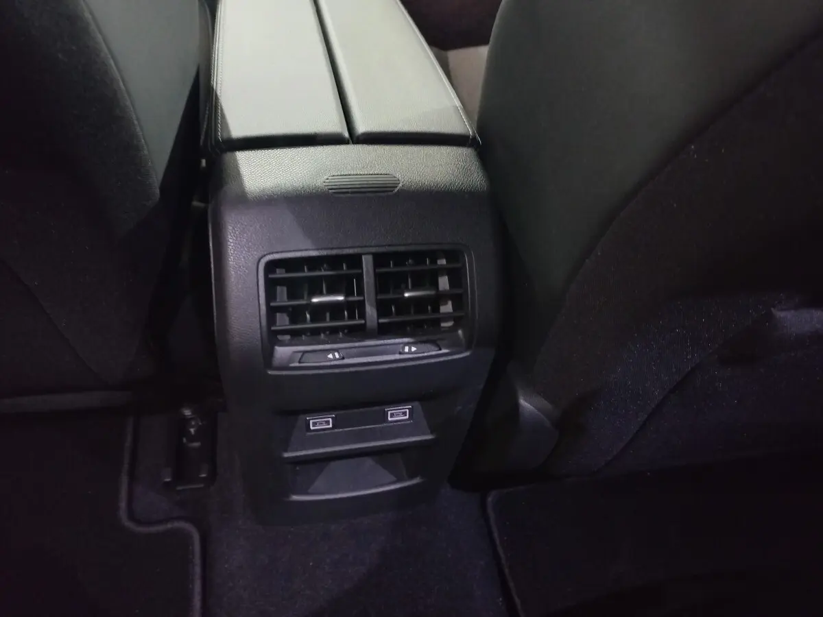 Vue rapprochée de la console centrale arrière noire avec bouches d’aération et ports USB de la Peugeot 308 PHEV 2025.