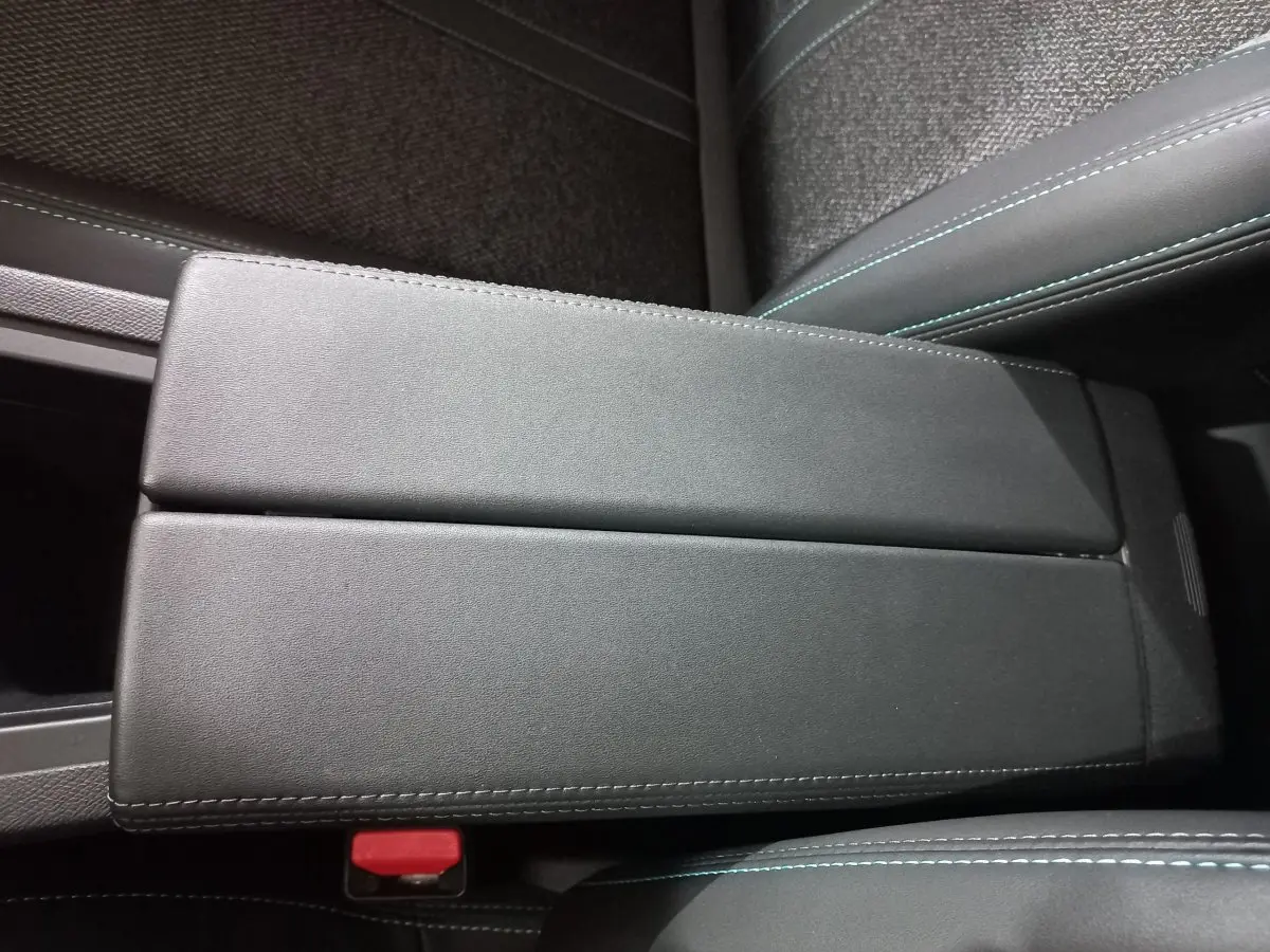 Accoudoir central en cuir noir avec surpiqûres bleues dans l’habitacle d’une Peugeot 308 PHEV 180 E-EAT8 Allure 2025.