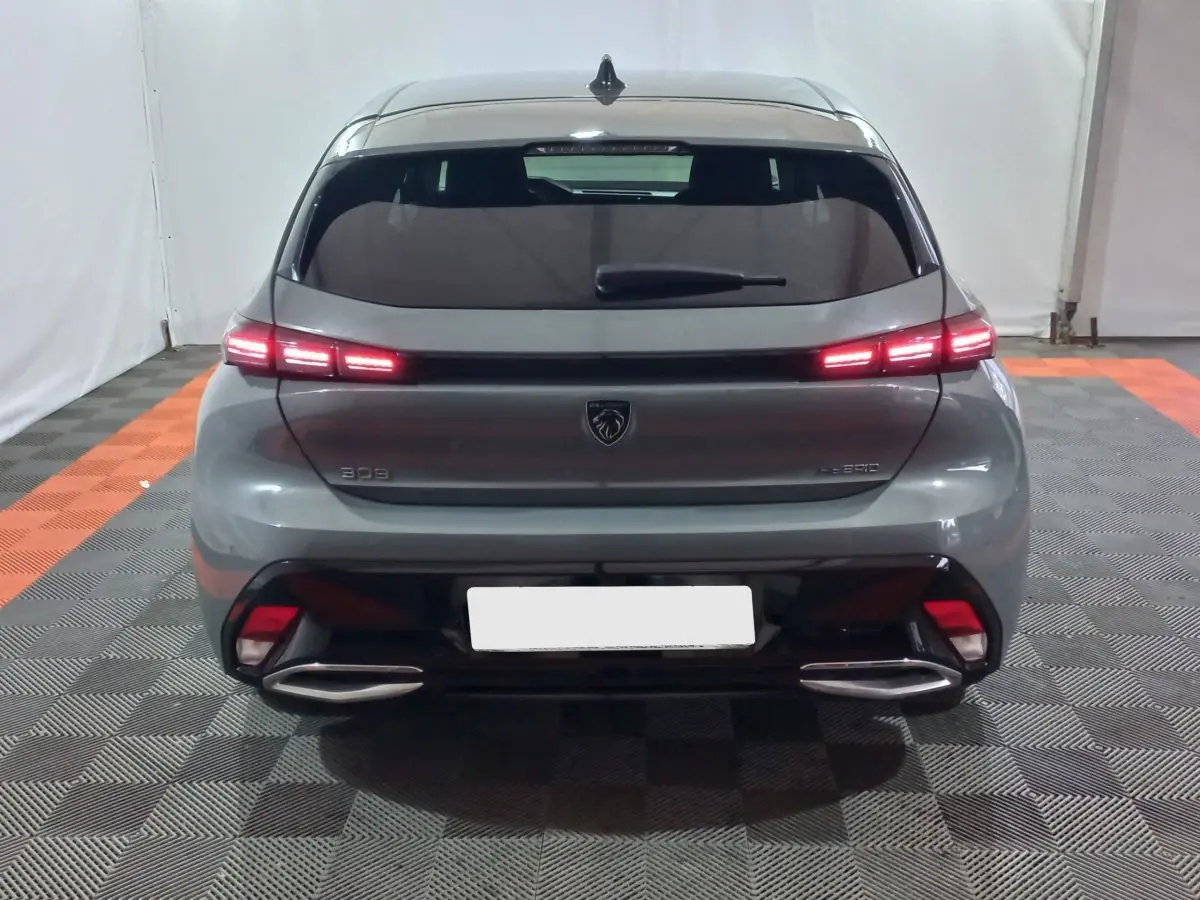 Vue arrière d’une Peugeot 308 PHEV 180 E-EAT8 Allure gris foncé avec feux LED allumés et double sortie d’échappement.