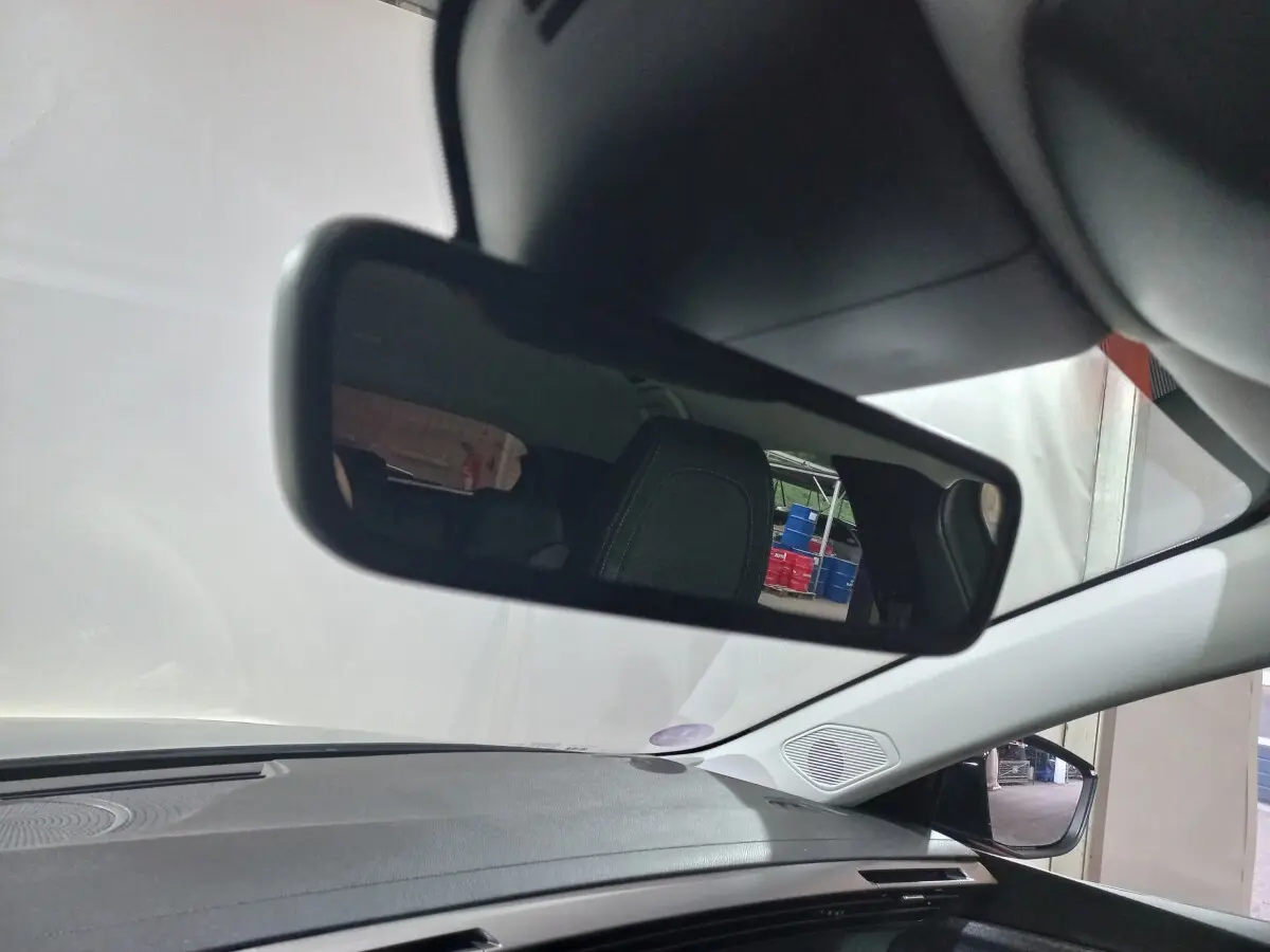 Vue intérieure du rétroviseur central d'une Peugeot 308 PHEV 180 E-EAT8 Allure 2025, avec tableau de bord gris et siège arrière visible.