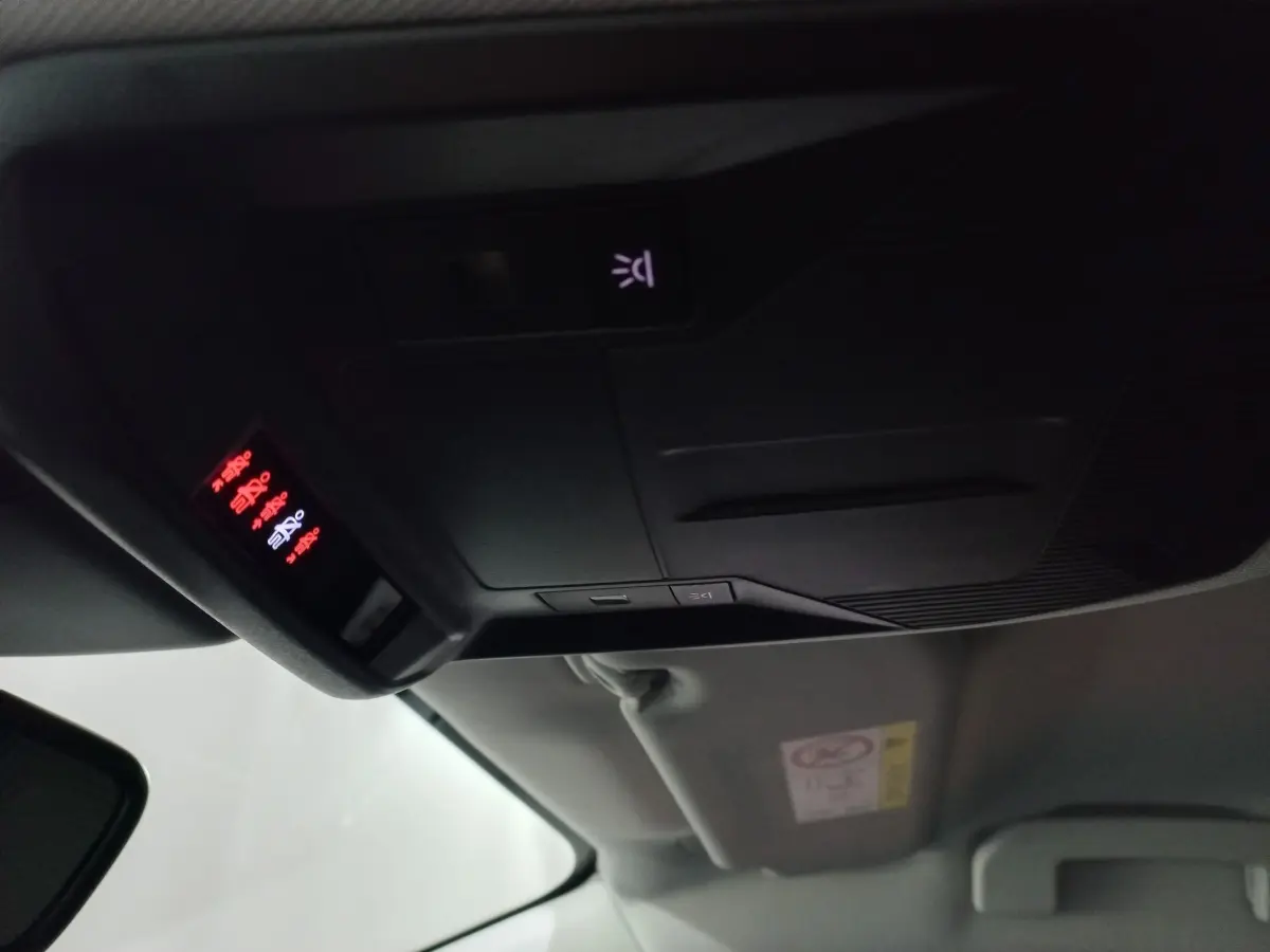 Vue intérieure du plafond avant de la Peugeot 308 PHEV 2025, avec commandes d’éclairage et affichage lumineux rouge.