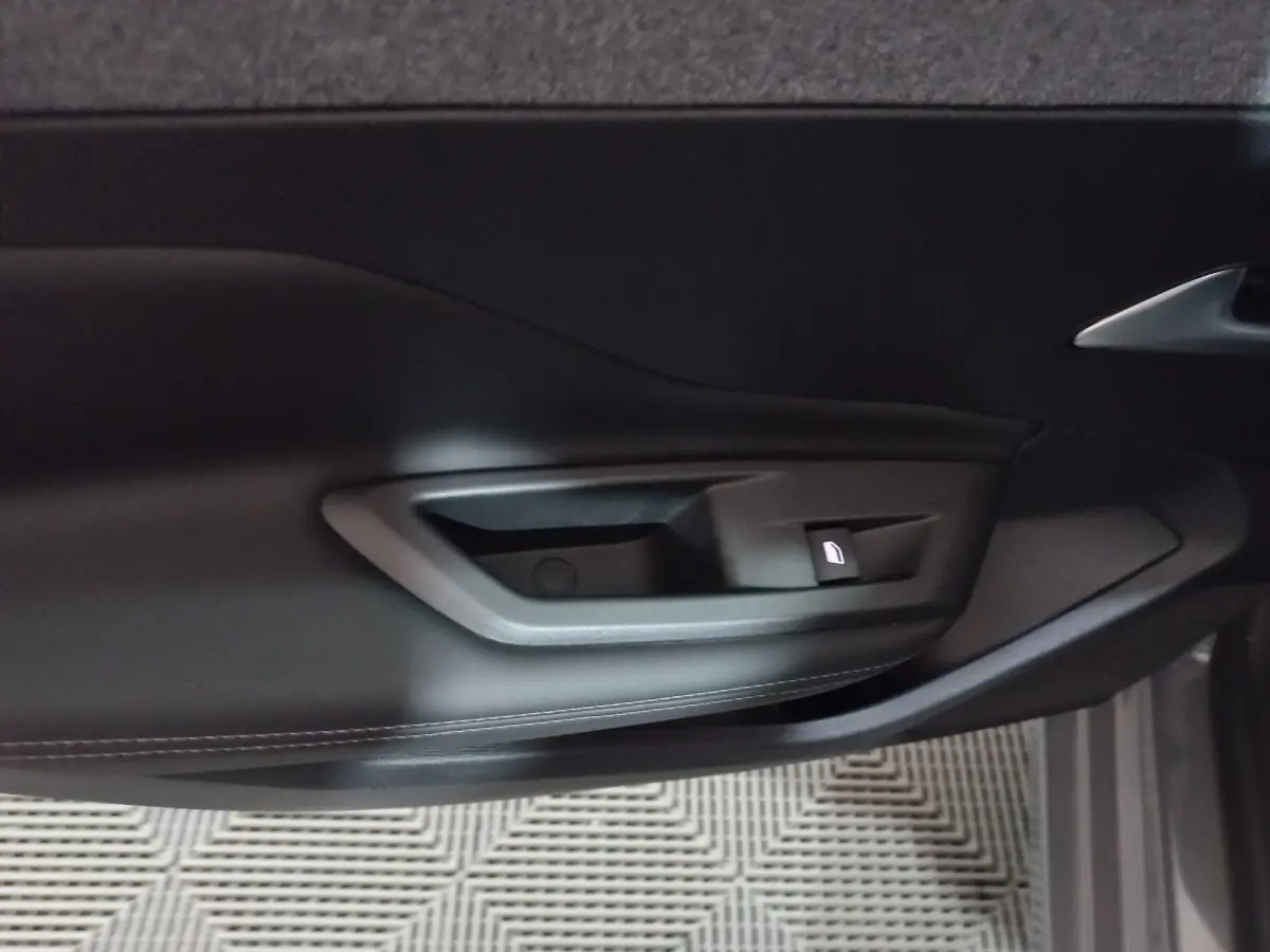 Poignée intérieure de porte côté gauche en plastique noir de la Peugeot 308 PHEV 180 E-EAT8 Allure 2025.
