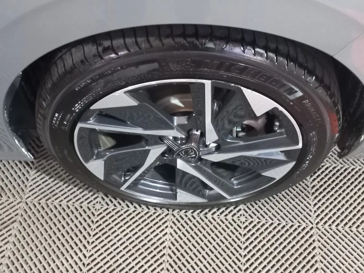 Gros plan sur la roue avant droite de la Peugeot 308 PHEV 180 E-EAT8 Allure gris foncé, jante alliage stylisée.