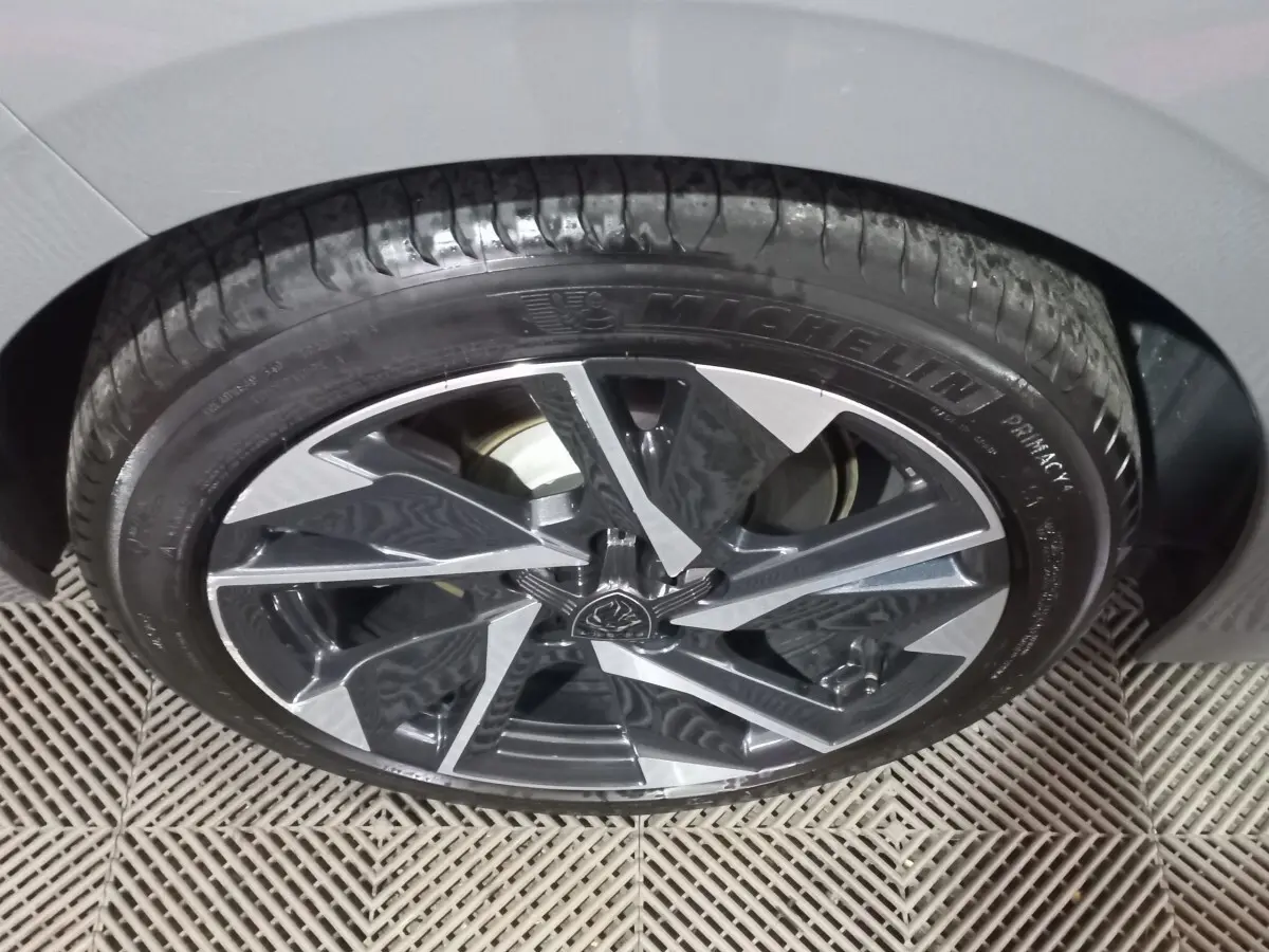 Gros plan sur la roue avant droite de la Peugeot 308 PHEV 180 E-EAT8 Allure gris foncé avec jante alliage stylisée.