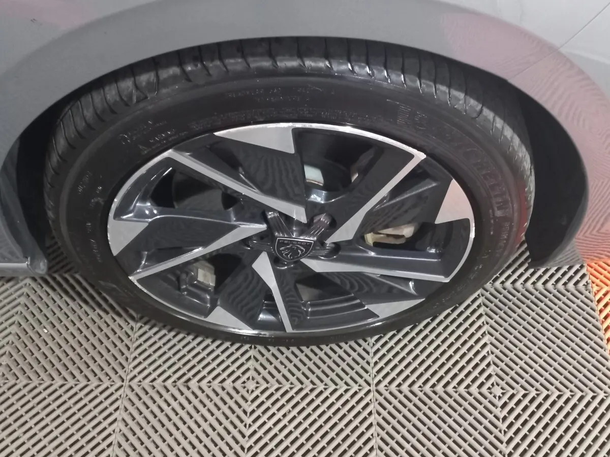 Gros plan sur la roue avant droite de la Peugeot 308 PHEV 180 E-EAT8 Allure gris foncé avec jante alliage noire et argent.