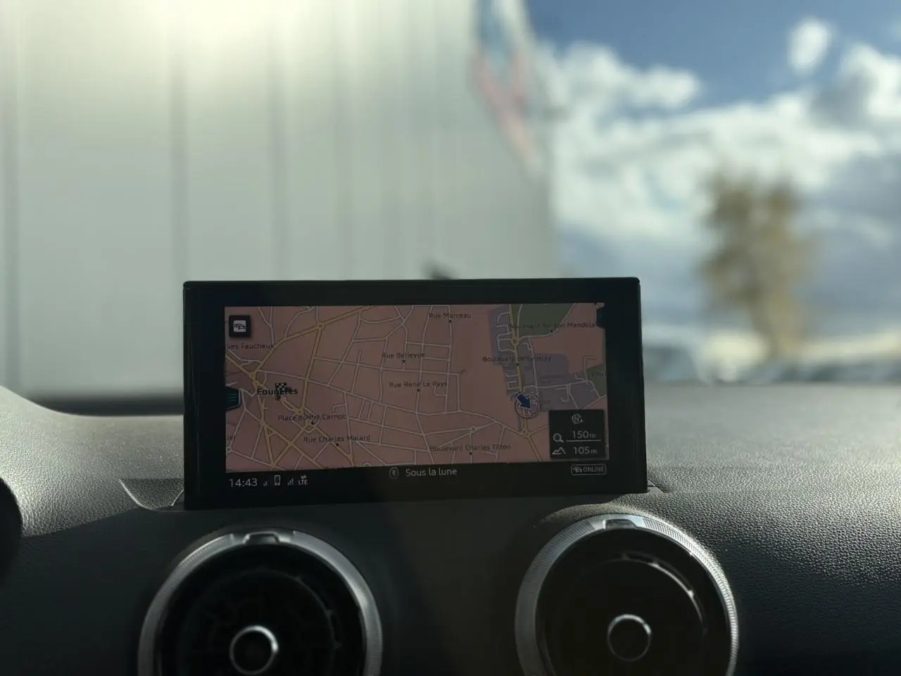 Écran de navigation central avec carte affichée, entouré de deux aérateurs ronds sur le tableau de bord noir.