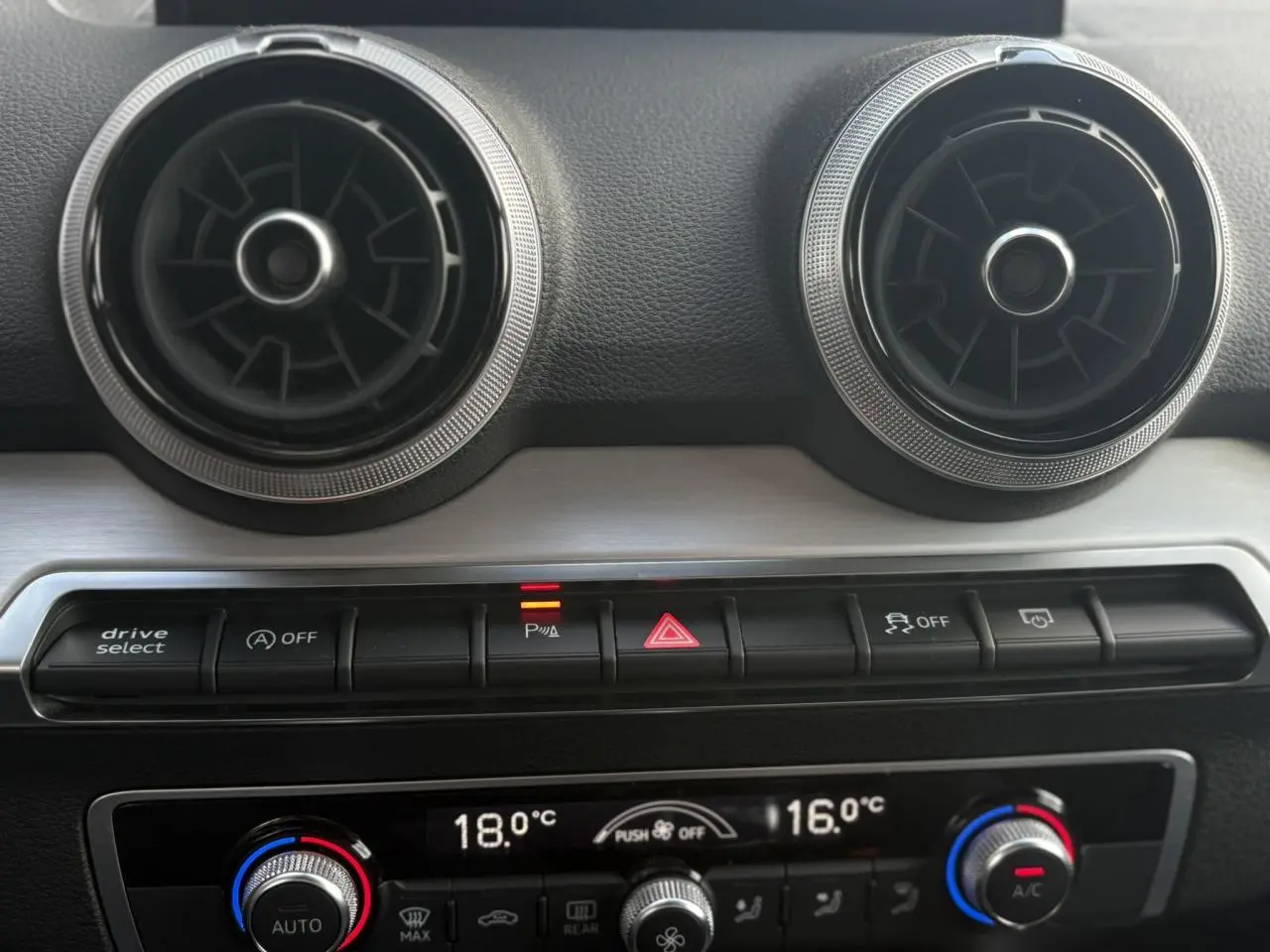 Détail du tableau de bord de l’Audi Q2 30 TFSI S-Line 2024 montrant les aérateurs ronds et commandes climatisation automatique.