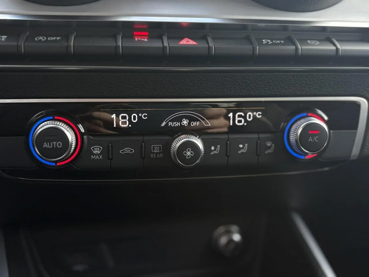 Gros plan sur la commande de climatisation automatique bi-zone du tableau de bord de l'Audi Q2 rouge Progressif 2024.