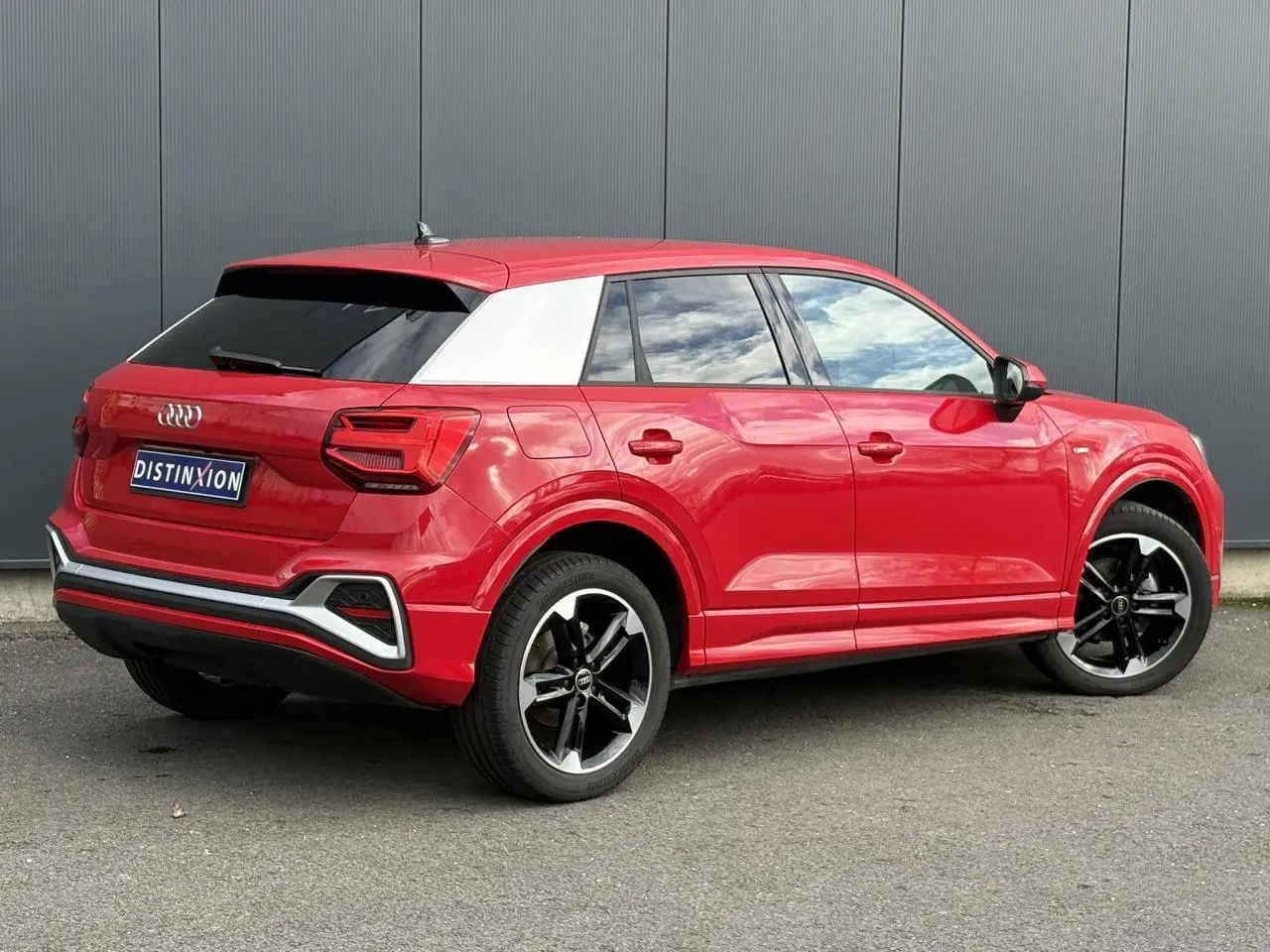 Audi Q2 30 TFSI S-Line rouge Progressif en 3/4 arrière droit, avec toit contrasté blanc et jantes noires polies.