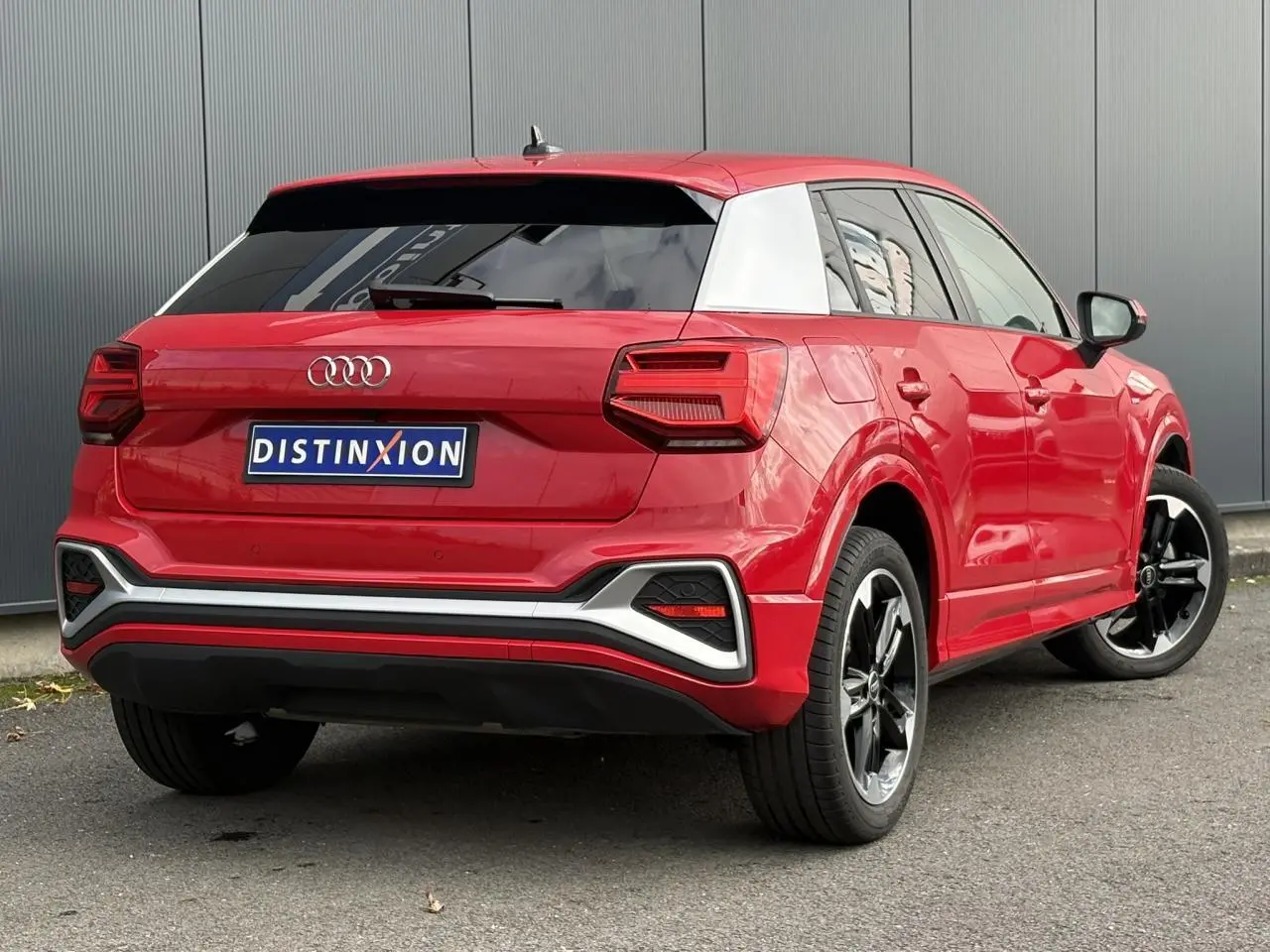 Audi Q2 30 TFSI S-Line rouge Progressif vue 3/4 arrière droit avec jantes alliage noir poli et toit contrasté blanc.