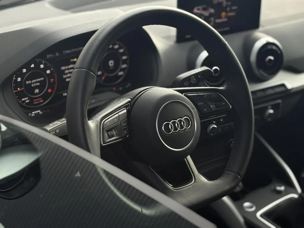 Vue rapprochée du volant cuir multifonction et du tableau de bord numérique de l'Audi Q2 30 TFSI S-Line 2024.