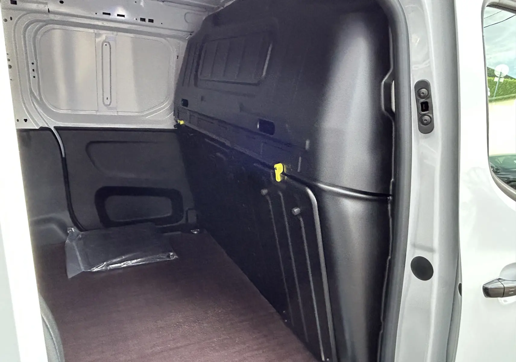 Vue intérieure du coffre du Peugeot Partner Fourgon blanc, mettant en valeur le plancher bois et la cloison noire.