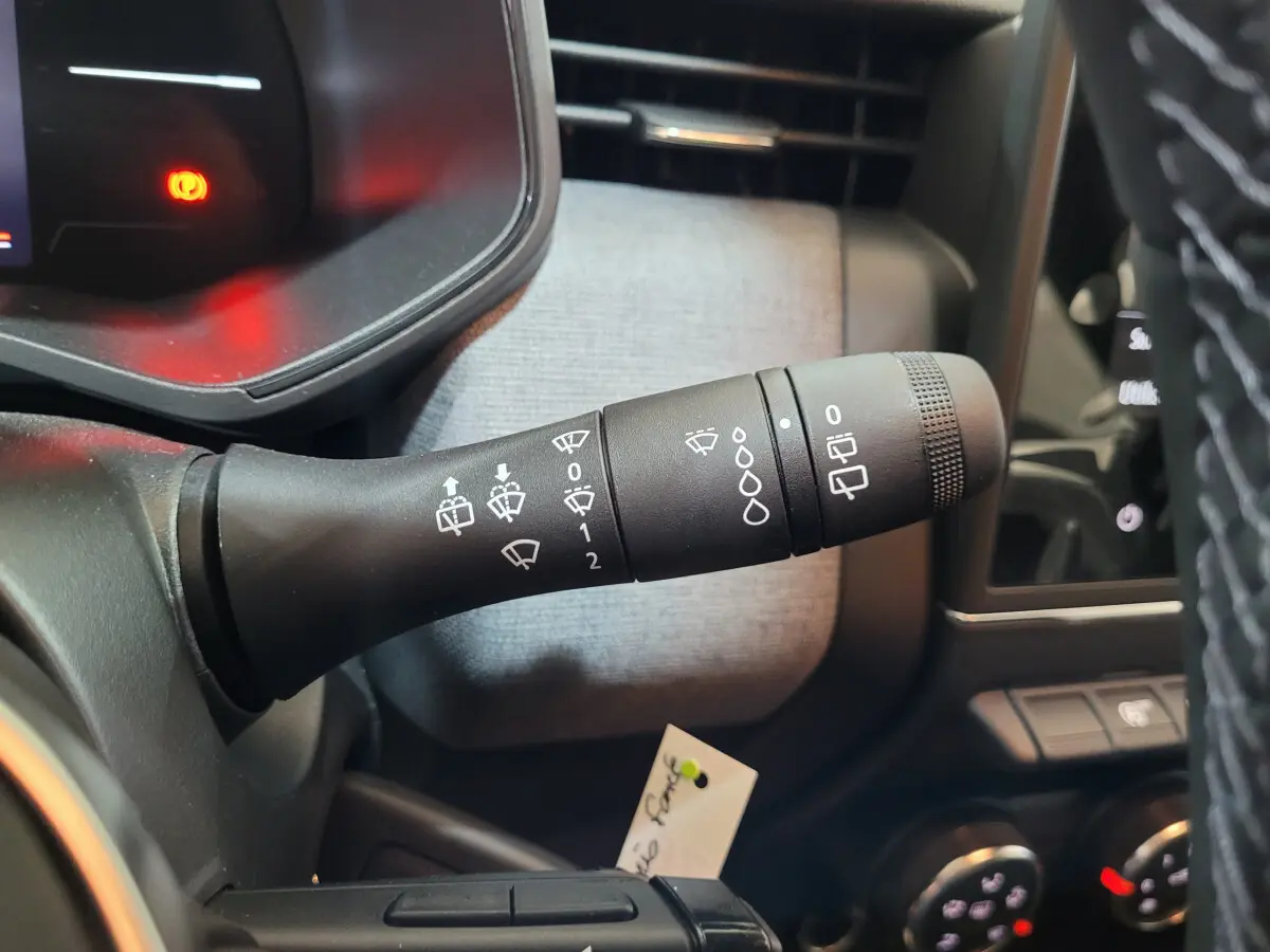 Gros plan sur la commande d’essuie-glace à gauche du volant dans l’habitacle gris clair de la Renault Clio gris foncé.