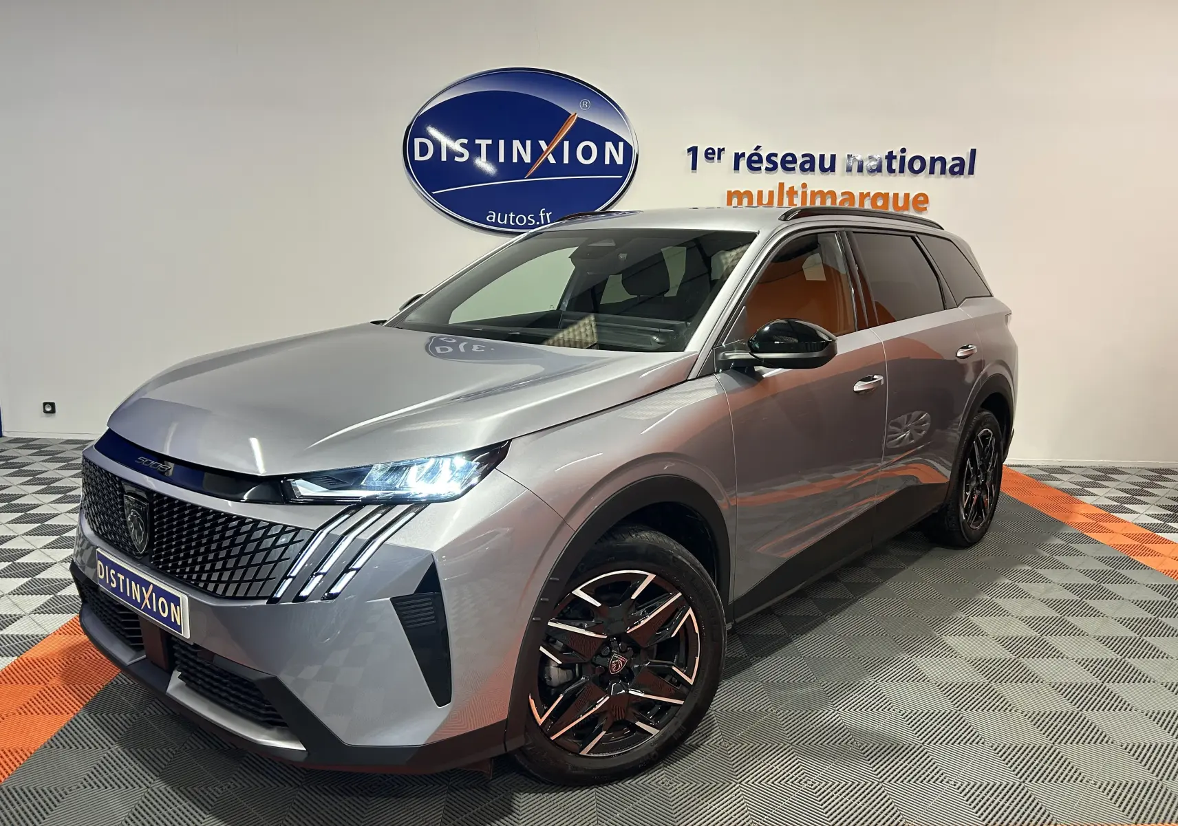Peugeot 5008 gris Artense en 3/4 avant droit, avec phares LED allumés et jantes noires brillantes.