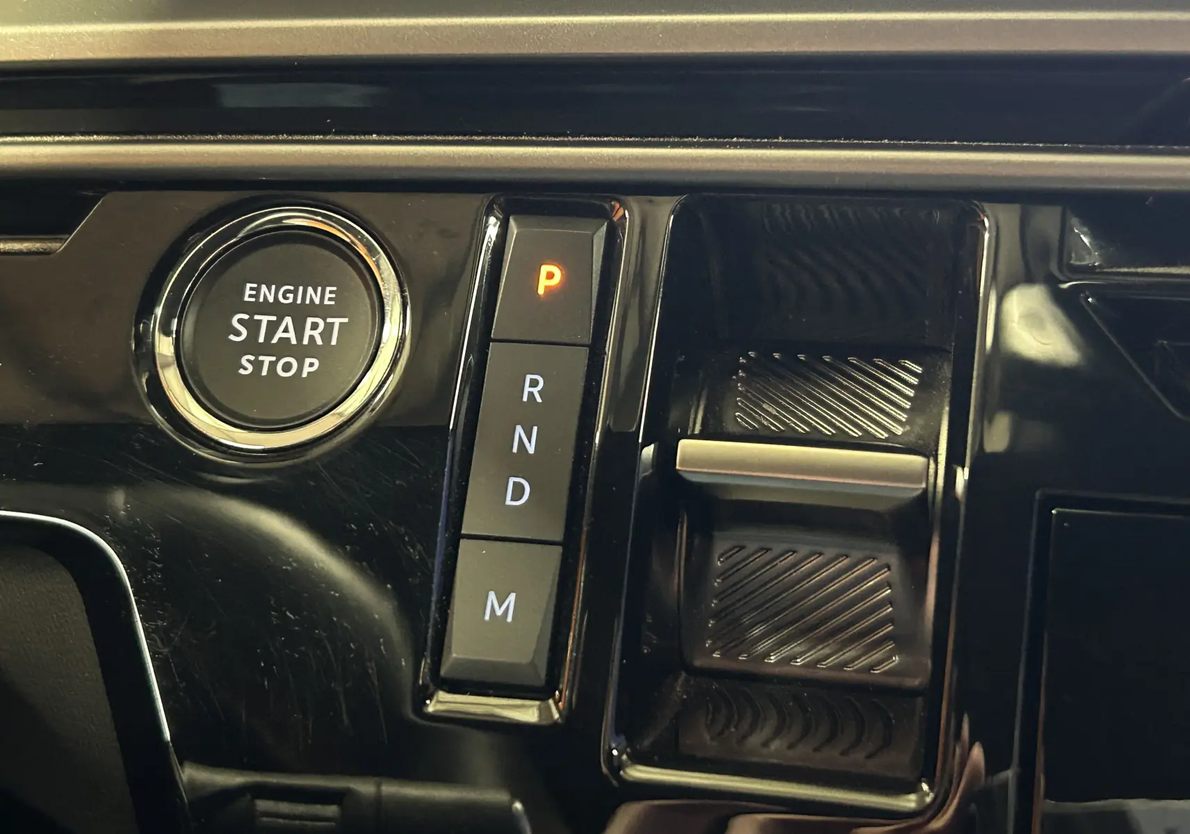 Gros plan sur la console centrale noire du Peugeot 5008 hybride 2025, avec bouton start/stop et sélecteur de boîte automatique.