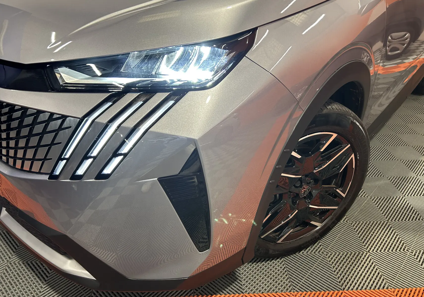 Gros plan sur l'avant droit gris Artense du Peugeot 5008 2025, mettant en valeur le phare LED et la jante noire stylisée.
