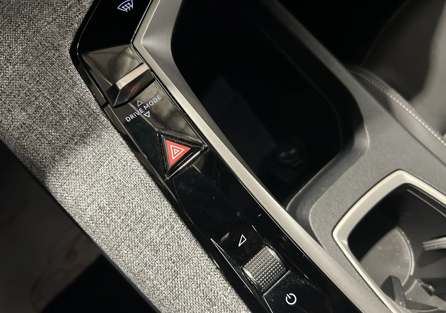 Détail de la console centrale noire et grise du Peugeot 5008 hybride 2025 avec bouton de mode de conduite et signal d’alerte.