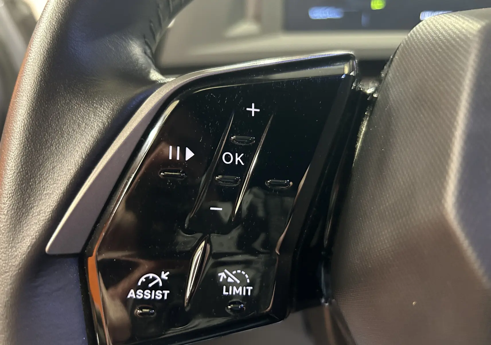 Gros plan sur les commandes noires du volant du Peugeot 5008 gris Artense, avec boutons Assist et Limit visibles.
