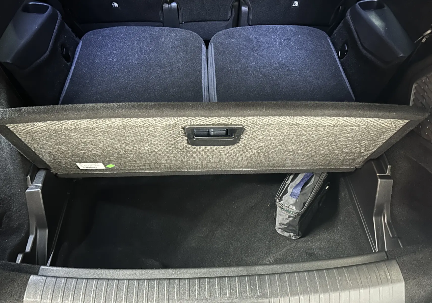 Vue plongeante sur le coffre ouvert du Peugeot 5008 gris Artense, montrant le compartiment de rangement sous plancher.