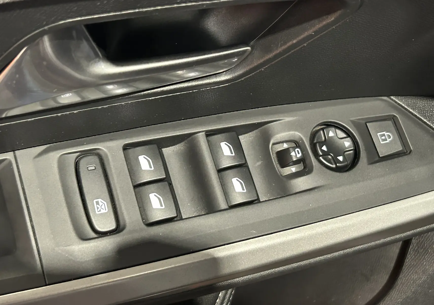 Gros plan sur les commandes de lève-vitres et rétroviseurs côté gauche intérieur du Peugeot 5008 gris Artense.