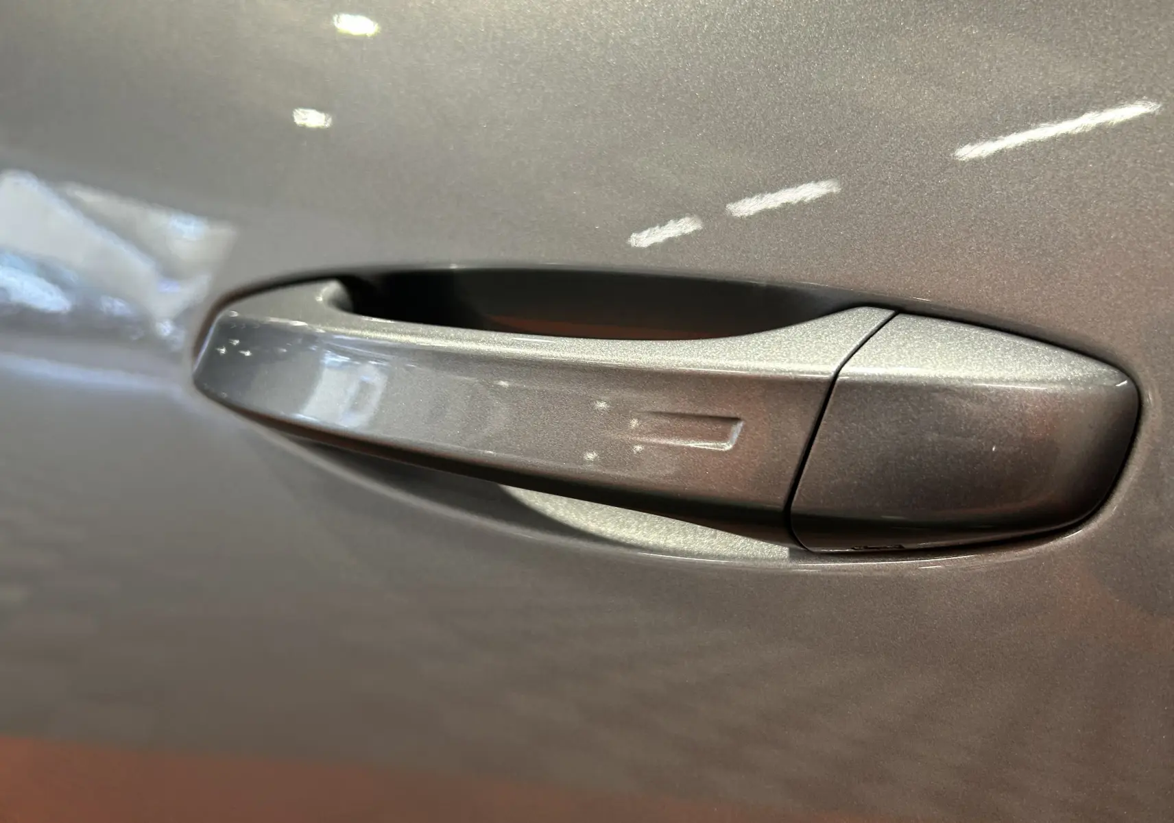 Poignée de porte gris Artense en gros plan sur Peugeot 5008 III Hybrid 145 e-DCS6 Allure, finition métallique brillante.