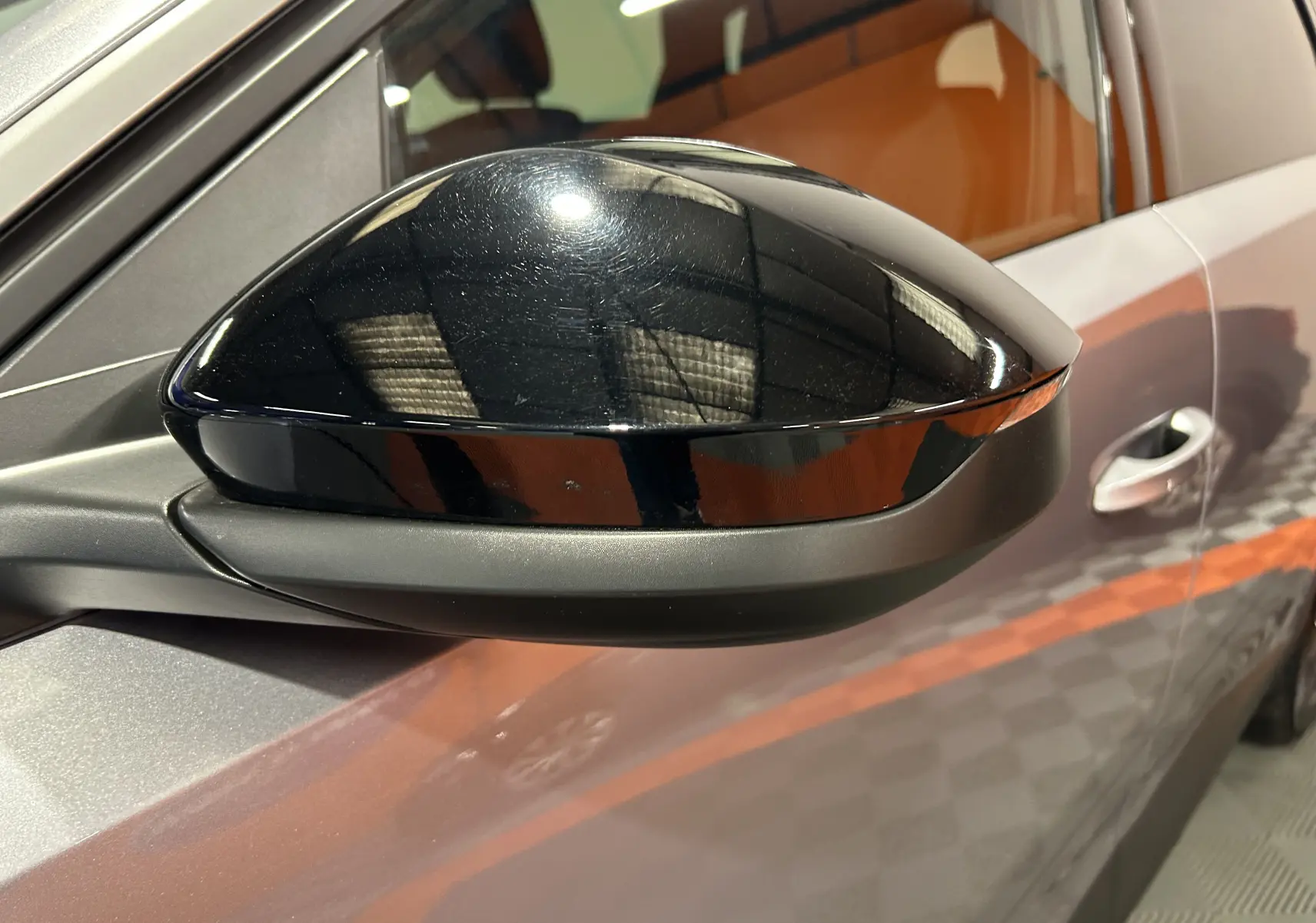 Gros plan sur le rétroviseur noir brillant côté gauche d’un Peugeot 5008 gris Artense, avec porte et vitre partiellement visibles.