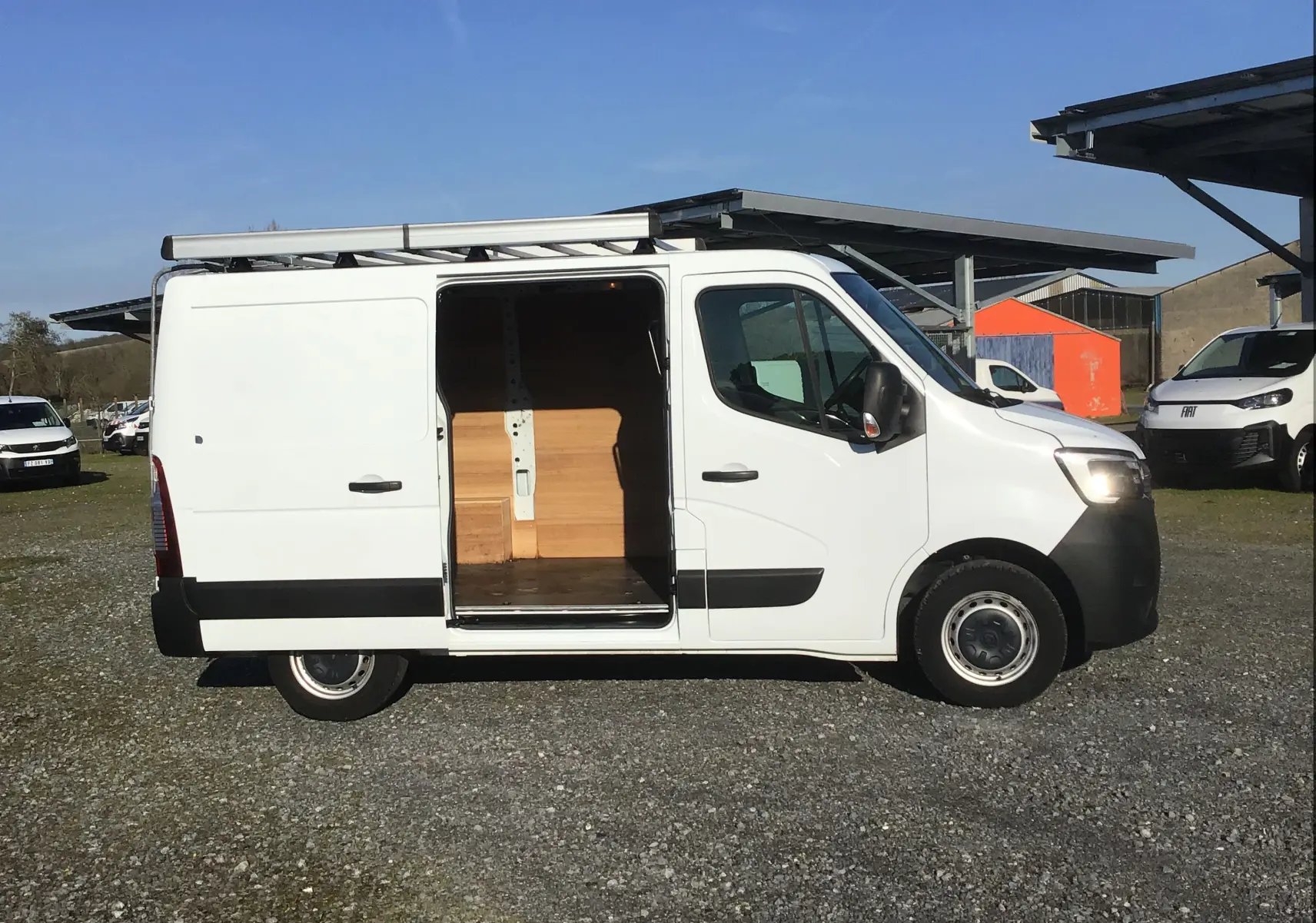 Vue de profil droit du Renault Master blanc 2022 avec porte latérale ouverte et galerie sur le toit.