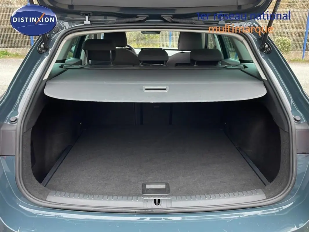 Coffre ouvert vu de l'arrière d'une SEAT Leon ST IV bleu avec cache bagages et intérieur spacieux.