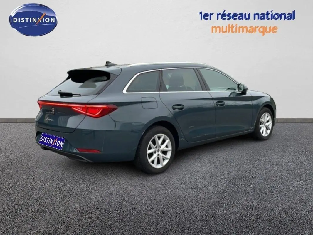 Vue 3/4 arrière droite d'une SEAT Leon ST bleu avec barres de toit et jantes aluminium sur fond neutre.