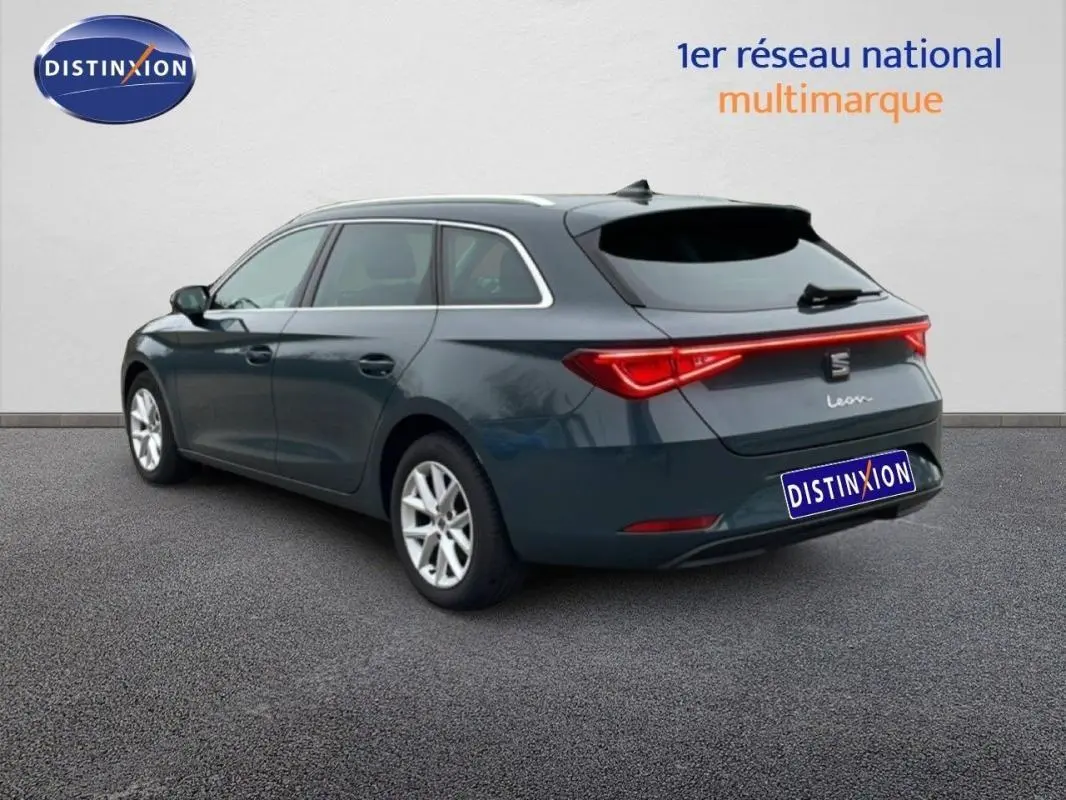 SEAT Leon ST bleu vue 3/4 arrière droit, barres de toit et feux arrière lumineux, jantes aluminium 16 pouces.