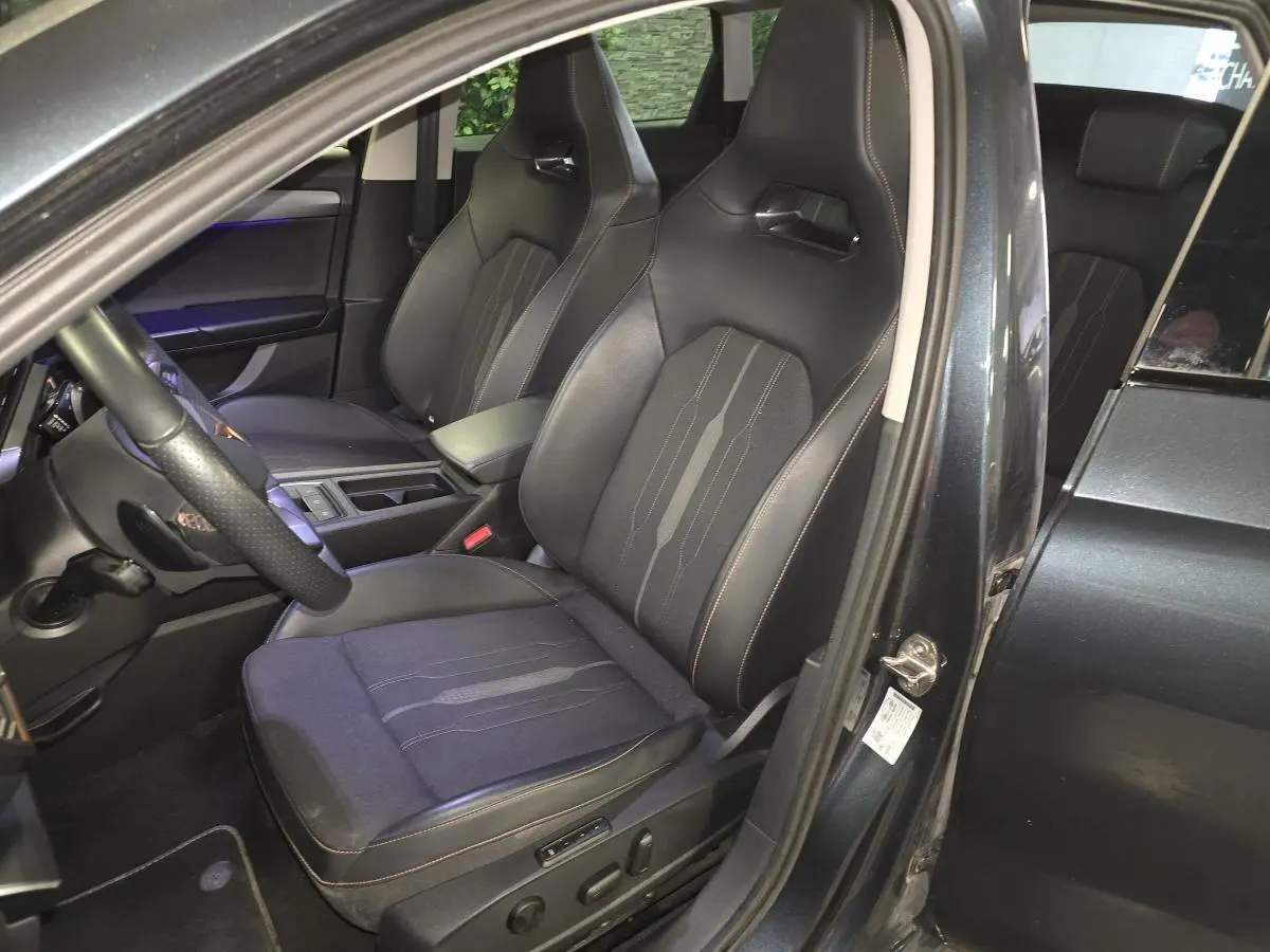 Vue intérieure côté conducteur du CUPRA Leon Sportstourer gris, mettant en valeur les sièges baquets noirs avec surpiqûres copper.