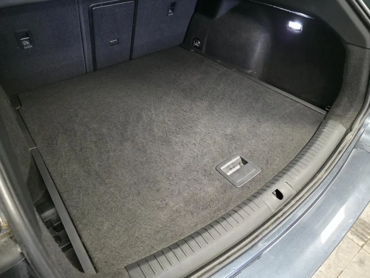 Coffre ouvert vu de dessus du CUPRA Leon Sportstourer gris avec tapis de sol et éclairage intérieur.