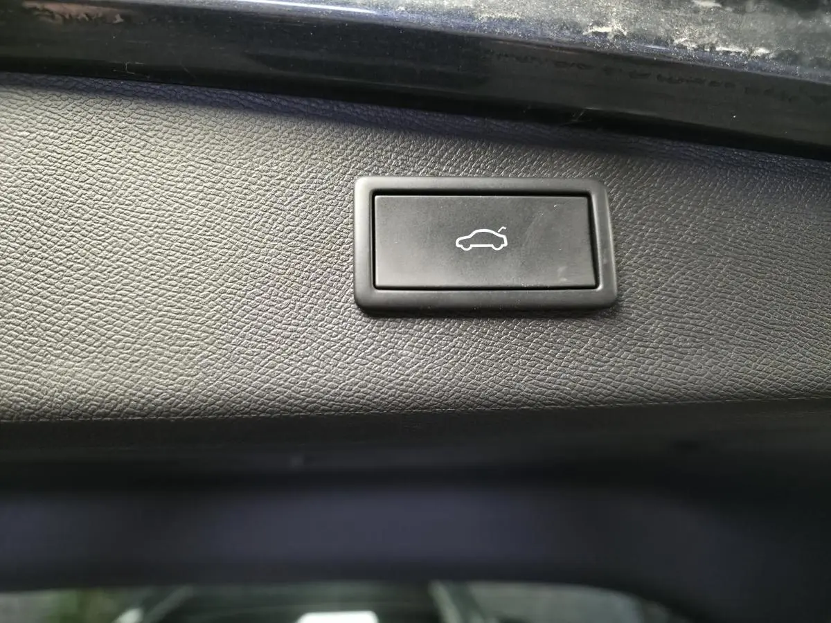 Bouton noir d'ouverture électrique du hayon sur la garniture intérieure d'un CUPRA Leon Sportstourer gris 2024.