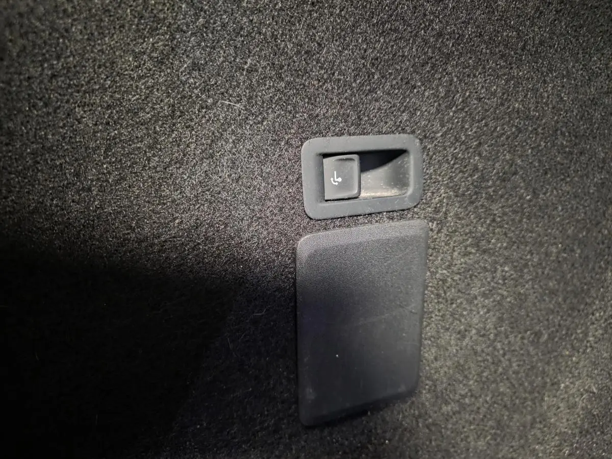 Détail du bouton de rabattement des sièges arrière dans le coffre du CUPRA Leon Sportstourer gris 2024.