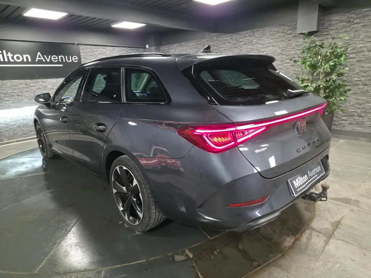Vue 3/4 arrière droite d'une CUPRA Leon Sportstourer gris magnétique avec feux arrière LED et crochet d'attelage visible.