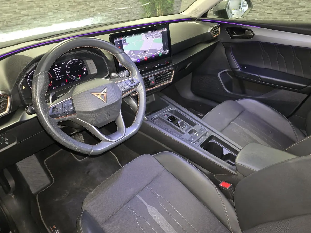 Vue intérieure côté conducteur de la CUPRA Leon Sportstourer 2024 avec tableau de bord digital et volant cuir noir surpiqué copper.