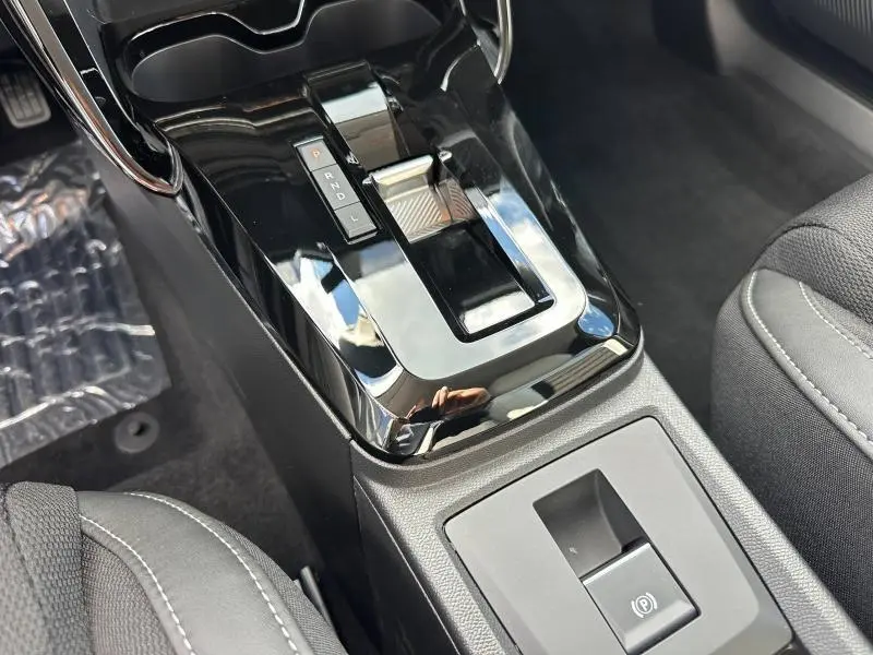 Gros plan sur la console centrale noire brillante avec levier de boîte automatique et bouton frein à main électrique du Citroën C3 Aircross.