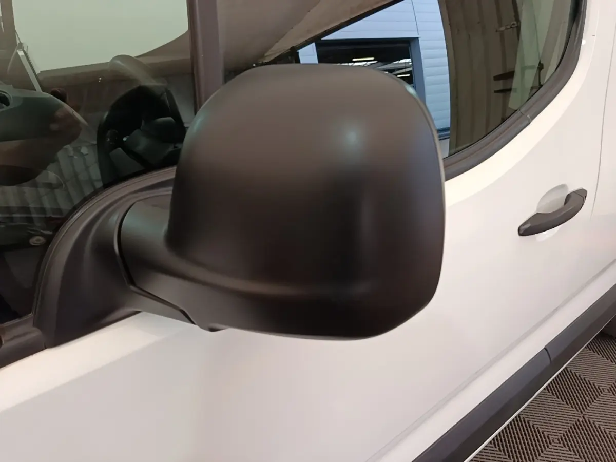 Gros plan sur le rétroviseur noir côté gauche du Citroën Berlingo blanc, avec porte et vitre visibles.