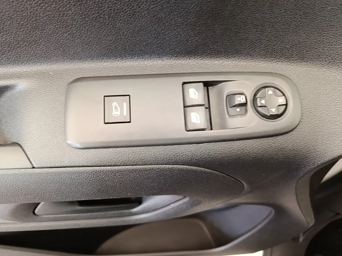 Gros plan sur les commandes de réglage des rétroviseurs et des vitres côté conducteur d’un Citroën Berlingo blanc.